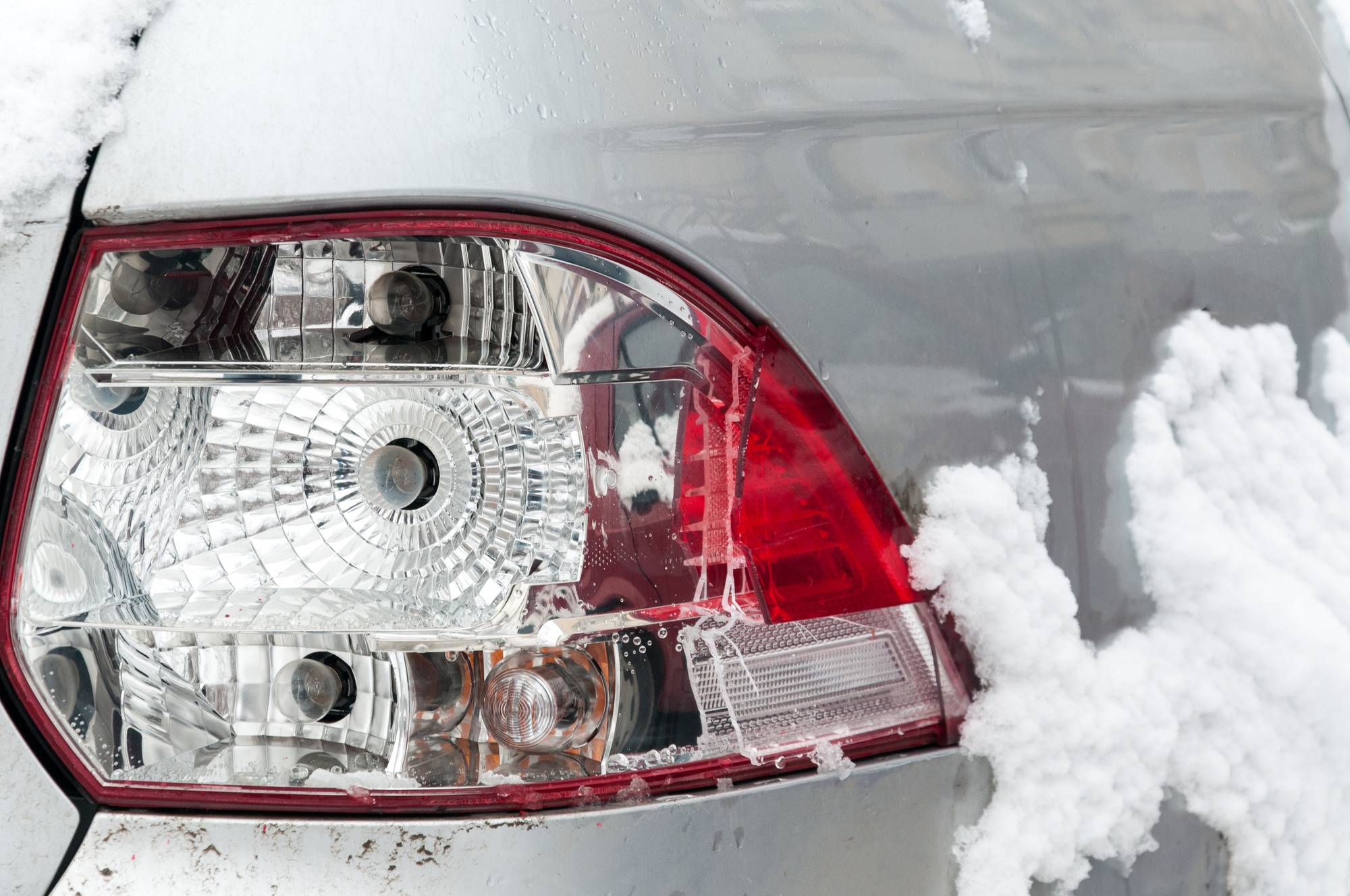 Damaged and broken rear stop or tail light of the silver car in